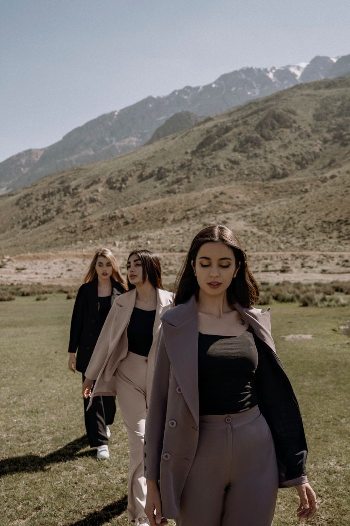 Crafting Captivating Headlines: Your awesome post title goes here Three stylish women in suits walk through a mountain landscape, embracing nature and fashion.