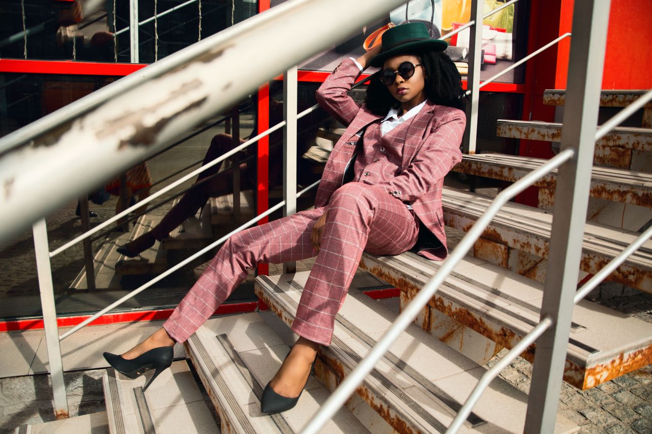 services-03 Fashionable woman in pink plaid suit and hat posing on an urban staircase.